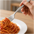 Mano enrollando espaguetis con un tenedor de acero inoxidable